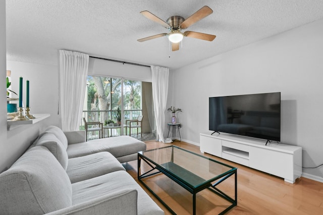 living area featuring baseboards, a textured ceiling, a ceiling fan, and wood finished floors