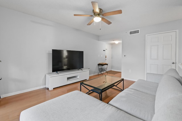 living room featuring wood-type flooring, a textured ceiling, and ceiling fan