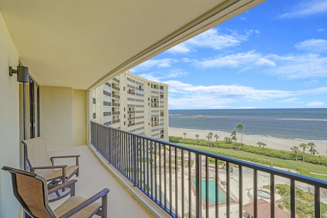 balcony featuring a view of the beach and a water view