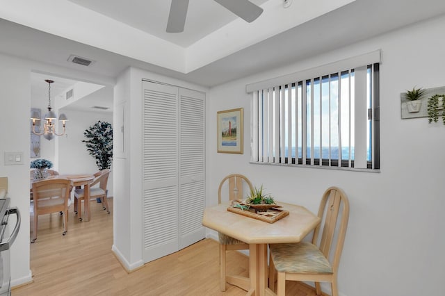 dining area with ceiling fan with notable chandelier and light hardwood / wood-style flooring