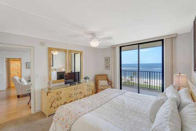 bedroom with access to outside, ceiling fan, light carpet, and a wall of windows