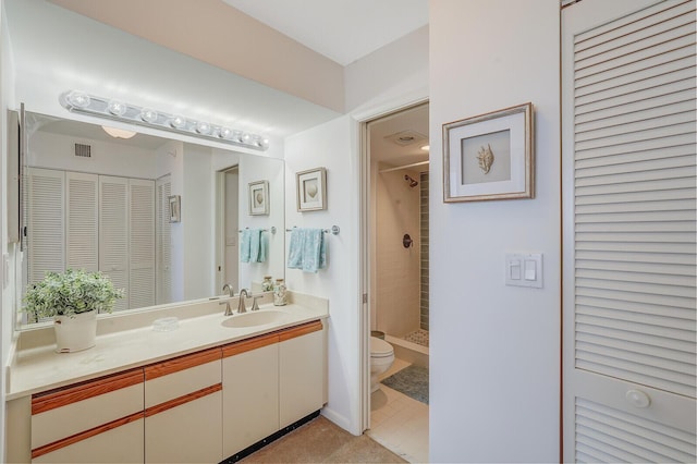 bathroom with a tile shower, vanity, and toilet