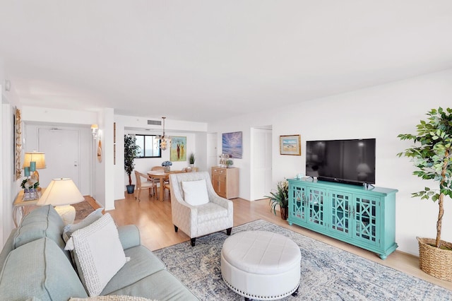 living room with light hardwood / wood-style floors and an inviting chandelier