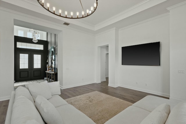 living room with an inviting chandelier, french doors, crown molding, a towering ceiling, and dark hardwood / wood-style flooring