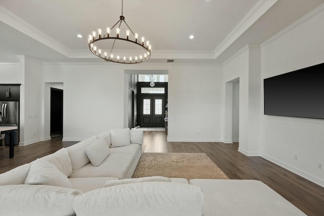 living room with dark hardwood / wood-style floors, crown molding, a tray ceiling, and an inviting chandelier