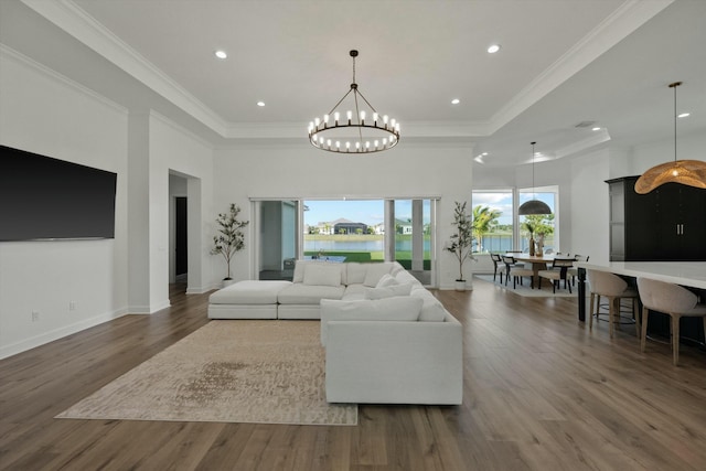 living room with a raised ceiling, crown molding, wood-type flooring, and an inviting chandelier