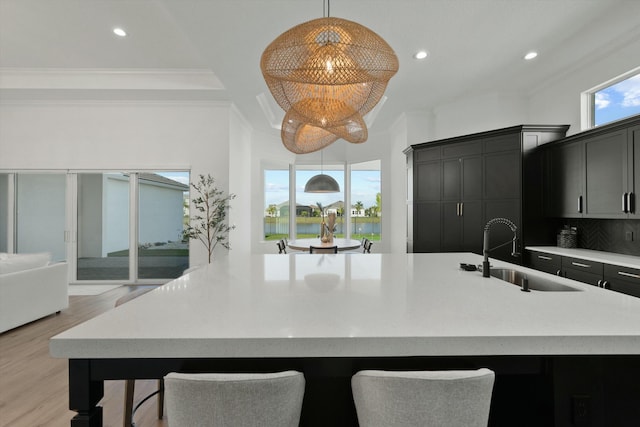 kitchen featuring pendant lighting, a spacious island, sink, crown molding, and decorative backsplash