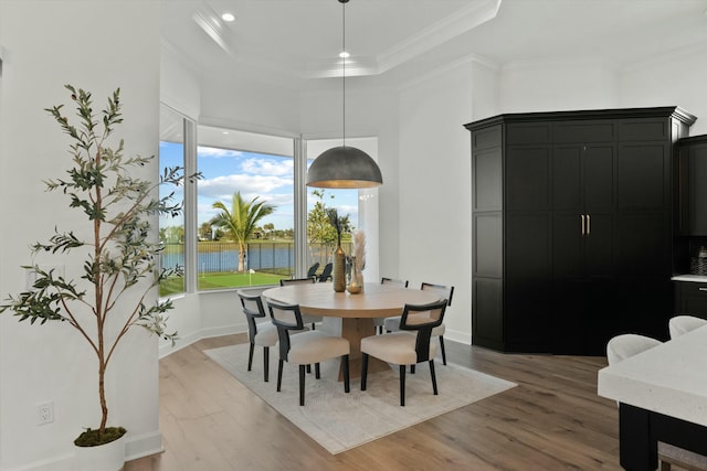 dining area featuring hardwood / wood-style flooring, a water view, and ornamental molding