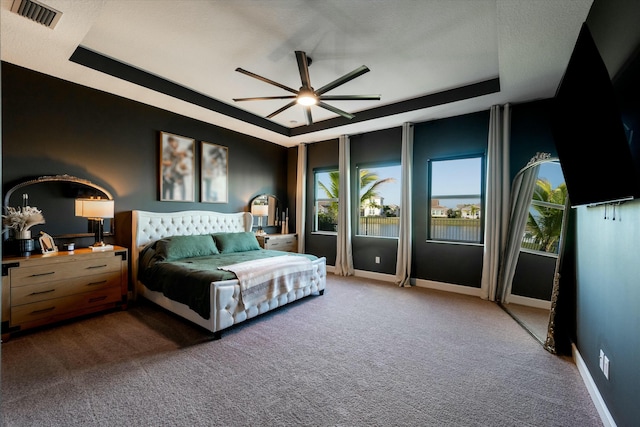 bedroom with carpet flooring, a raised ceiling, and ceiling fan