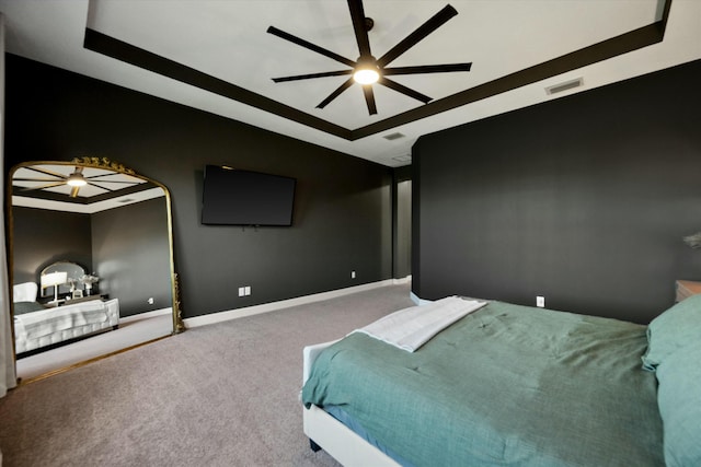 carpeted bedroom with ceiling fan and a tray ceiling