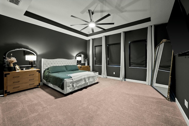 bedroom featuring ceiling fan, carpet floors, and a tray ceiling