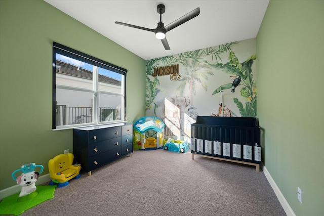 carpeted bedroom with ceiling fan and a nursery area