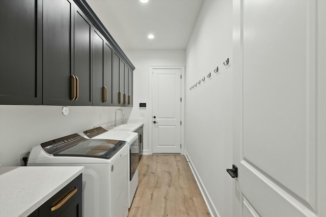 laundry room featuring separate washer and dryer, light hardwood / wood-style flooring, and cabinets