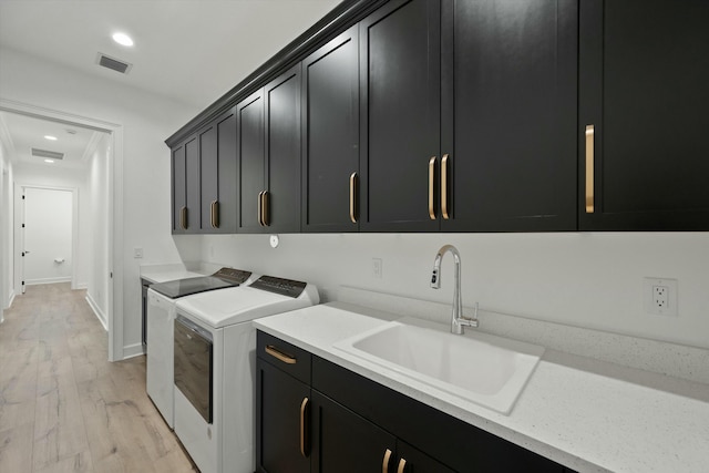 laundry area featuring cabinets, light hardwood / wood-style floors, washer and clothes dryer, and sink