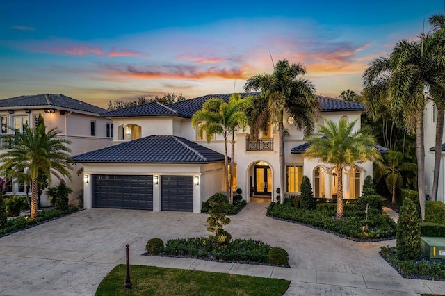 mediterranean / spanish-style home with a balcony, french doors, and a garage