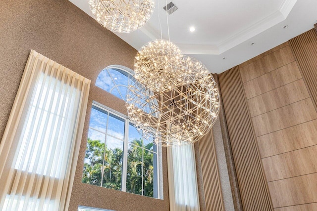 details with ornamental molding, a raised ceiling, and a notable chandelier