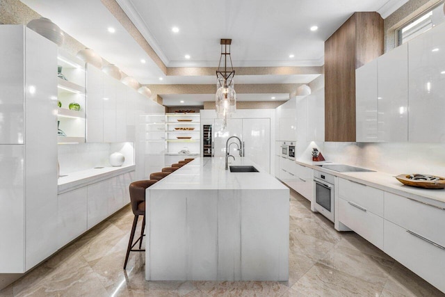 kitchen with a large island with sink, white cabinetry, and decorative light fixtures