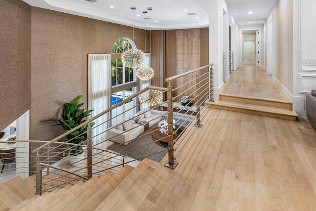 hall with light hardwood / wood-style floors, a raised ceiling, and crown molding