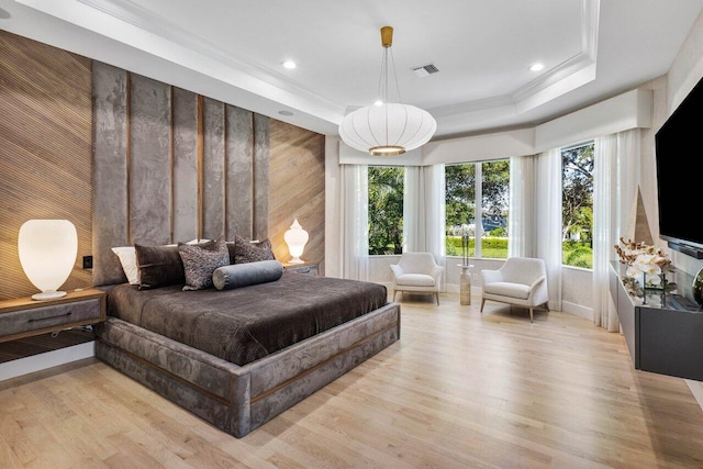 bedroom featuring light hardwood / wood-style floors, ornamental molding, and a tray ceiling