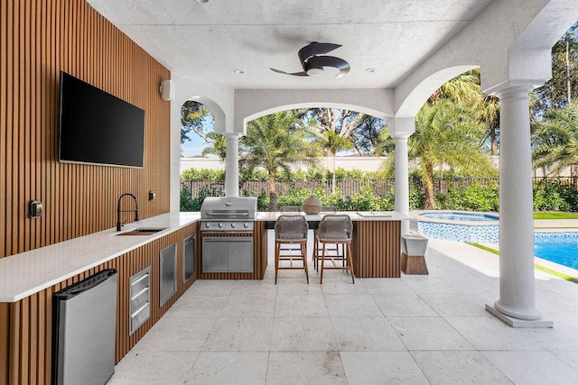 view of patio with ceiling fan, an outdoor wet bar, grilling area, a fenced in pool, and area for grilling