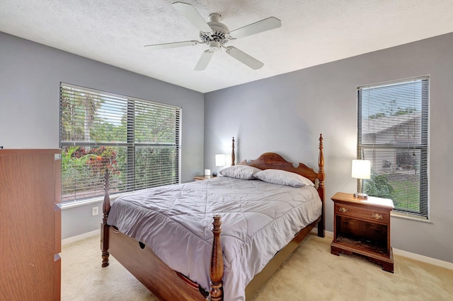 bedroom with ceiling fan, light carpet, and a textured ceiling