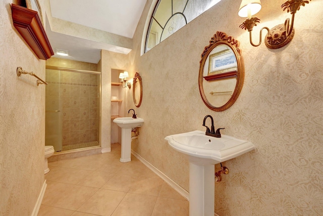 bathroom with toilet, tile patterned flooring, dual sinks, and a shower with door