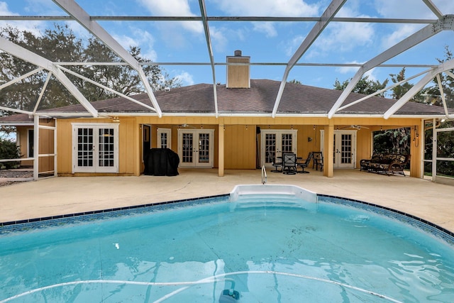 view of swimming pool featuring french doors, ceiling fan, glass enclosure, and a patio