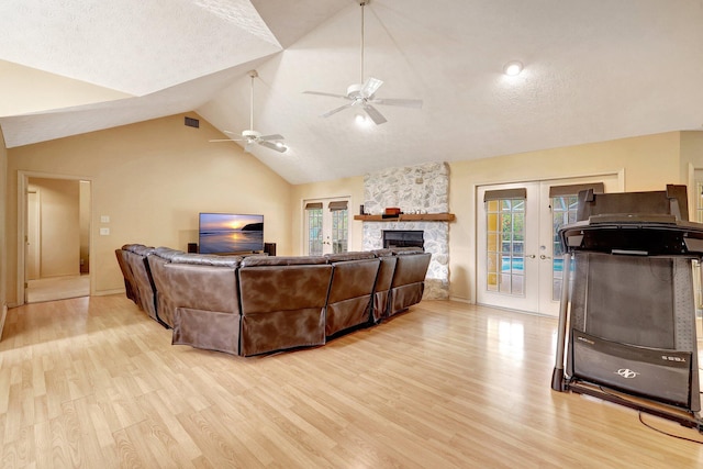 living room with lofted ceiling, french doors, a textured ceiling, and light hardwood / wood-style flooring