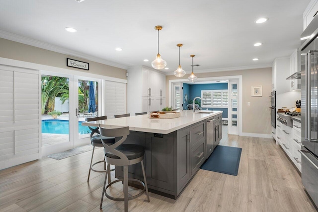 kitchen featuring a large island, gray cabinetry, light wood-type flooring, white cabinetry, and decorative light fixtures