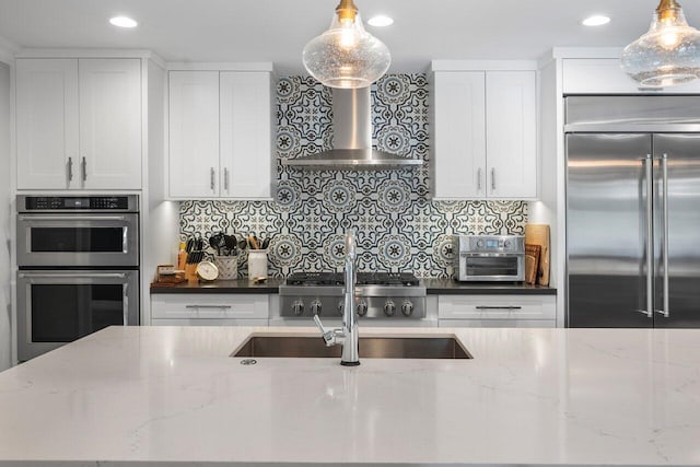 kitchen with decorative light fixtures, stainless steel appliances, dark stone counters, and white cabinetry