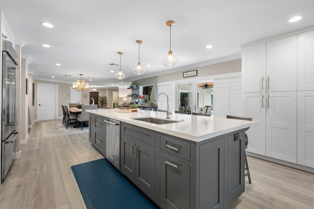 kitchen featuring gray cabinetry, hanging light fixtures, an island with sink, sink, and white cabinetry