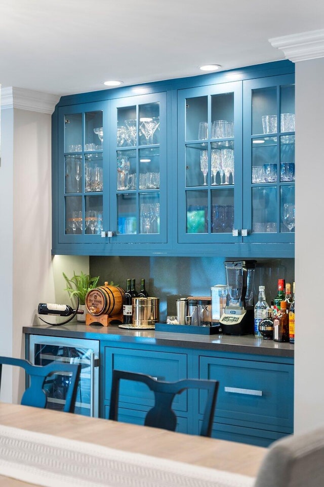 bar with blue cabinets, wine cooler, and crown molding