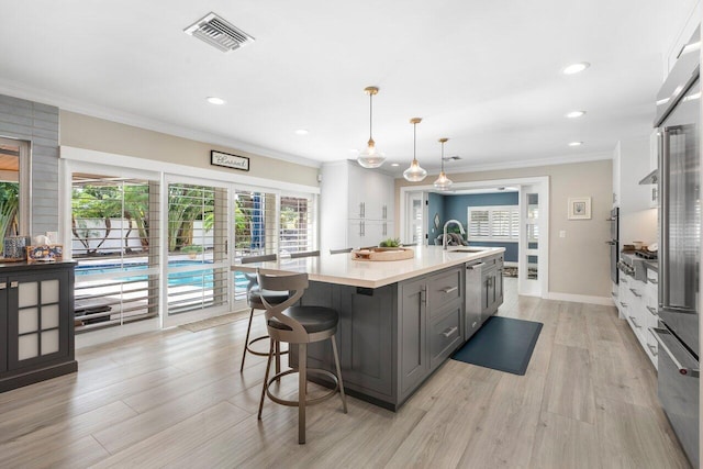 kitchen with an island with sink, gray cabinetry, light hardwood / wood-style floors, and pendant lighting