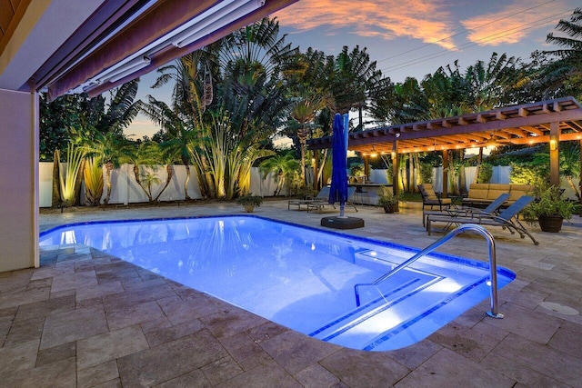 pool at dusk with a patio area and a pergola