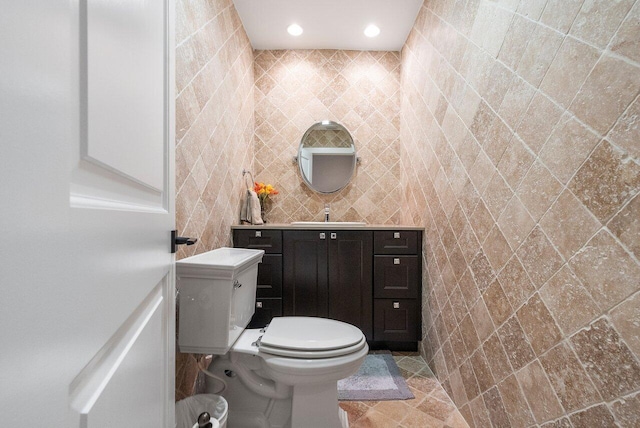 bathroom with sink, toilet, and tile walls