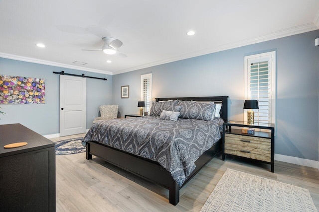 bedroom with ornamental molding, light wood-type flooring, ceiling fan, and a barn door