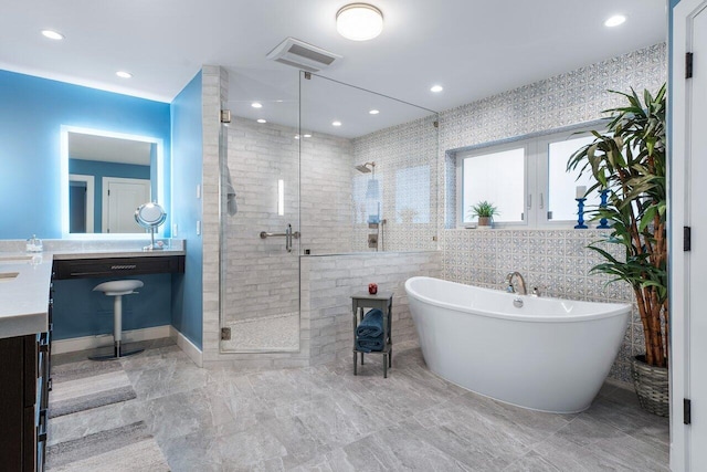 bathroom featuring tile walls, independent shower and bath, and vanity