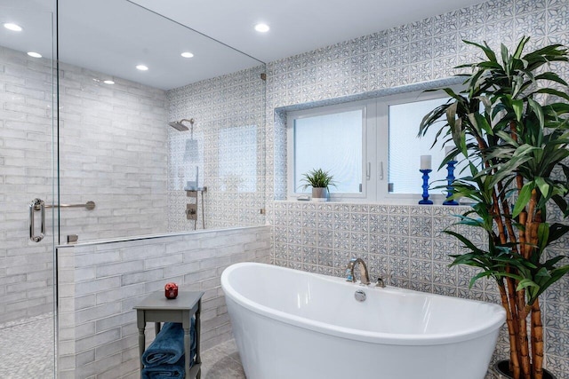 bathroom featuring shower with separate bathtub and tile walls