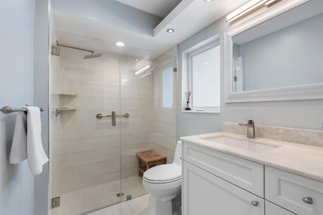 bathroom with toilet, vanity, and a shower with shower door