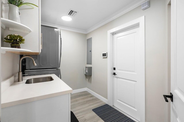 kitchen with light hardwood / wood-style floors, crown molding, electric panel, sink, and fridge