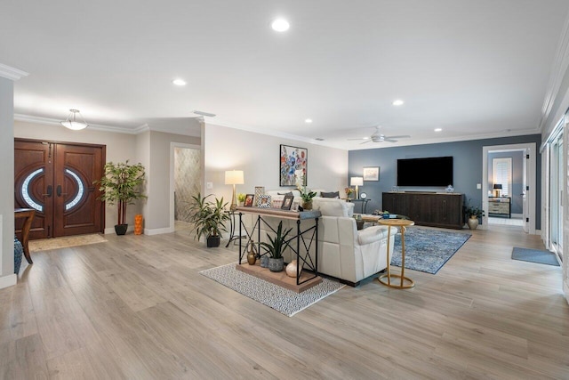 living room with light hardwood / wood-style floors, ceiling fan, and crown molding