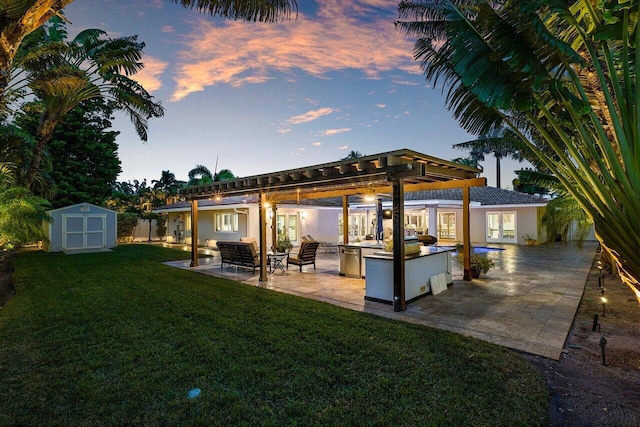 exterior space featuring a yard, an outdoor kitchen, a storage shed, and a patio area