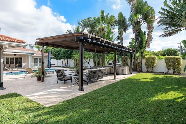 view of yard with a patio area, a pergola, an outdoor kitchen, a fenced in pool, and ceiling fan