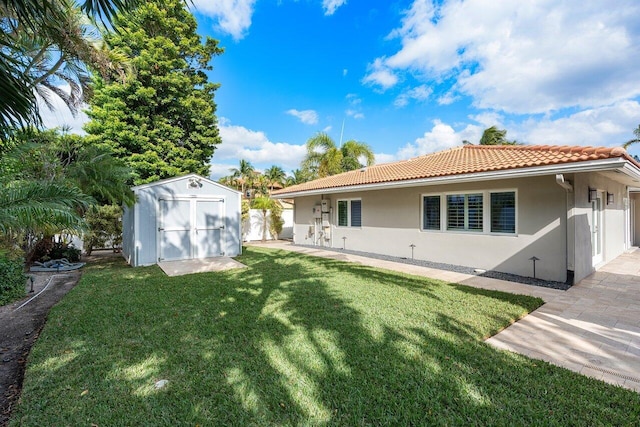 rear view of house featuring a yard and a storage unit