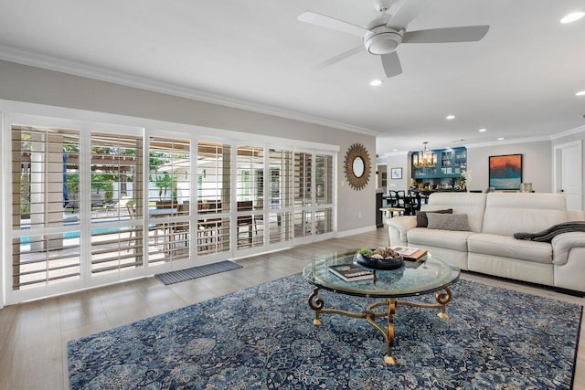 living room with ceiling fan with notable chandelier, hardwood / wood-style floors, ornamental molding, and plenty of natural light