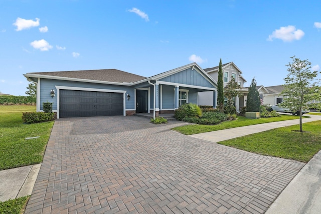 view of front of house featuring covered porch, a front yard, and a garage