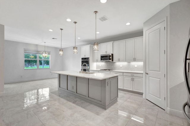 kitchen with sink, an island with sink, decorative light fixtures, white cabinetry, and stainless steel appliances