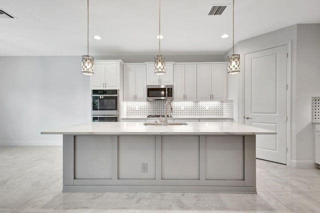 kitchen featuring appliances with stainless steel finishes, hanging light fixtures, a spacious island, and sink