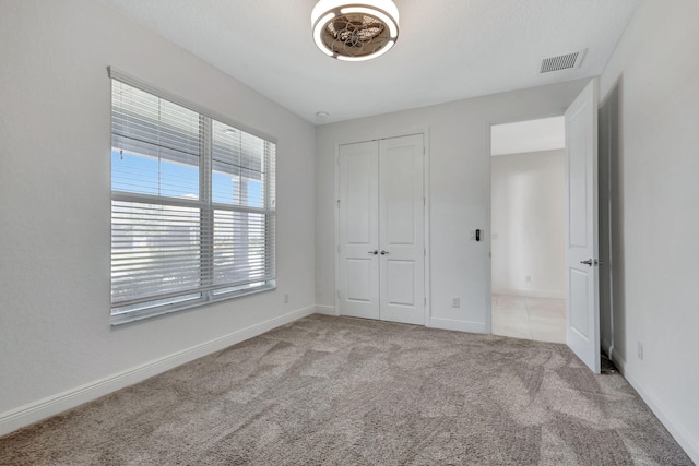 unfurnished bedroom featuring light colored carpet and a closet