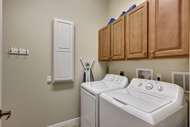 clothes washing area with cabinets and washer and dryer